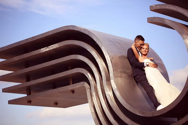 Novia y novio sentado en pieza metálica arquitectónica —  Fotos de Stock