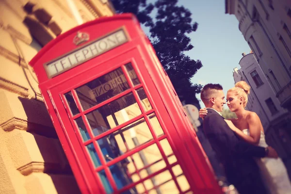 Sposa e sposo vicino alla cabina telefonica — Foto Stock