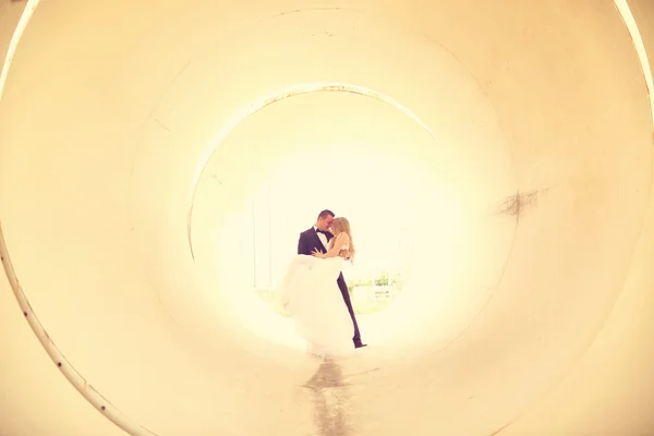 Noiva e noivo posando em um tubo — Fotografia de Stock