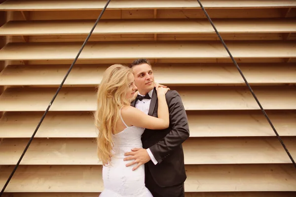 Bride and groom posing against striped wall — Stock Photo, Image