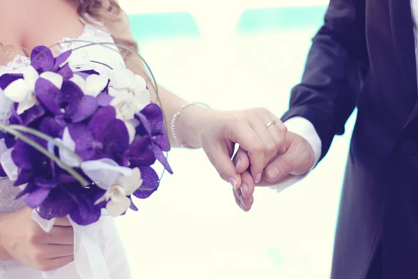 Hands of bride and groom with bouquet — Stock Photo, Image