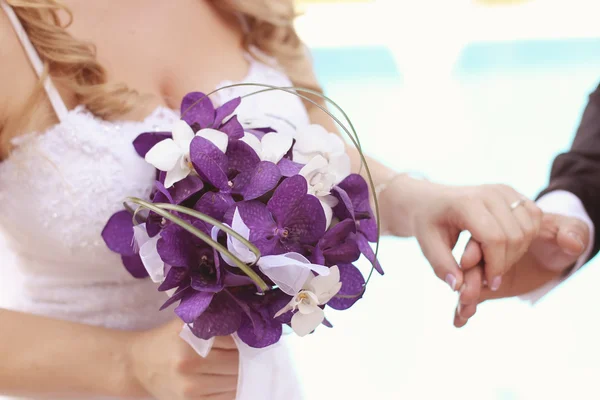 Hands of bride and groom with bouquet — Stock Photo, Image