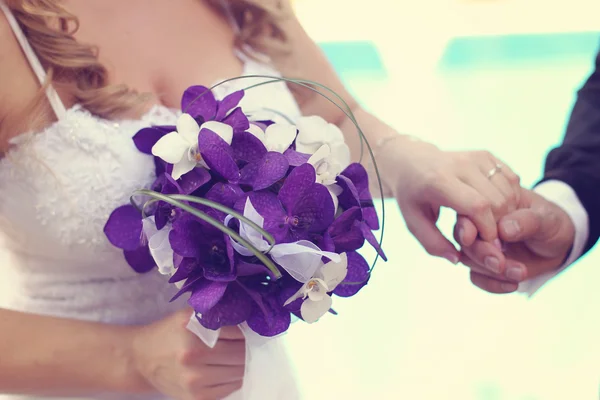 Hands of bride and groom with bouquet — Stock Photo, Image