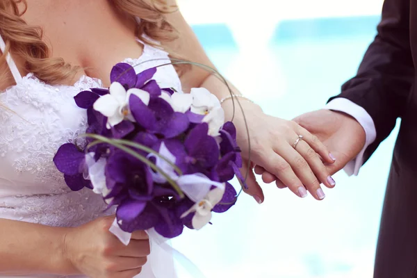 Hands of bride and groom with bouquet — Stock Photo, Image