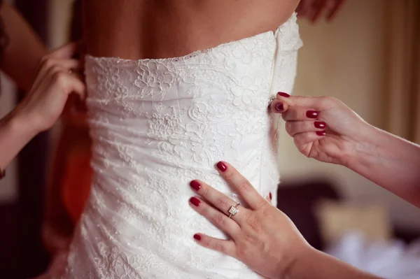 Bridesmaid helping the bride with dress — Stock Photo, Image