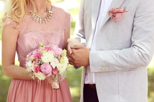 シャクヤクの花束を持つ女性の手を握っているカップル — ストック写真