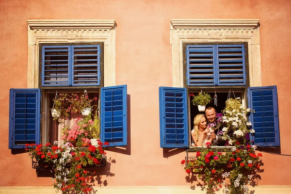 Braut und Bräutigam amüsieren sich aus Fenster des alten Hauses — Stockfoto