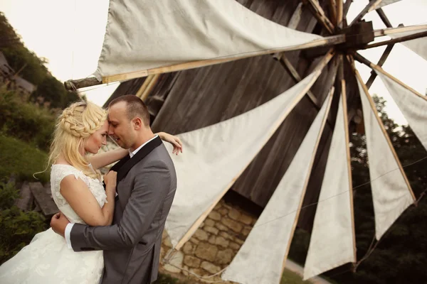 Novia y novio posando en un hermoso paisaje, cerca de un molino de viento — Foto de Stock