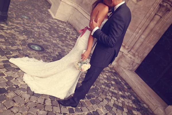 Detalhe de uma noiva e noivo abraçando. Noiva segurando lindo buquê de casamento — Fotografia de Stock