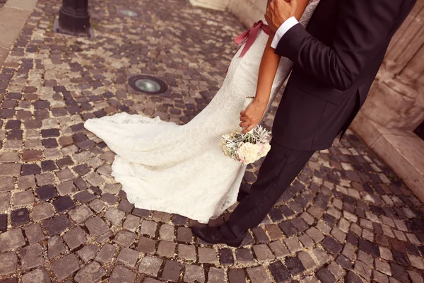 Detalj av en brud och brudgum embracing. Brud holding vackra bröllop bukett — Stockfoto