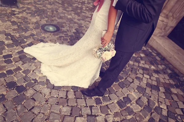 Detail van een bruid en een bruidegom omarmen. Bruid houden van mooie bruiloft boeket — Stockfoto