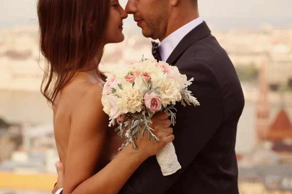 Detalhe de uma noiva e noivo abraçando. Noiva segurando lindo buquê de casamento — Fotografia de Stock