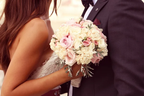 Detalj av en brud och brudgum embracing. Brud holding vackra bröllop bukett — Stockfoto