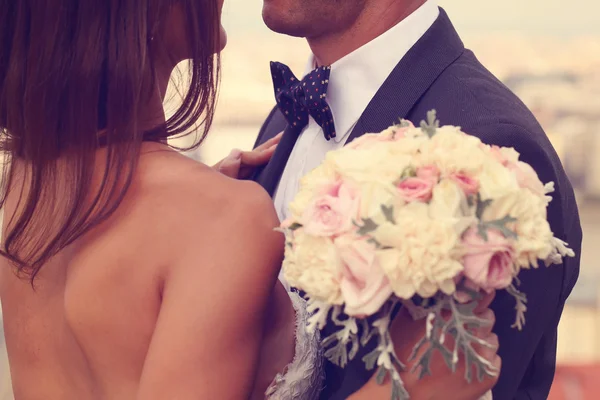 Detail of a bride and groom embracing. Bride holding beautiful wedding bouquet — Stock Photo, Image