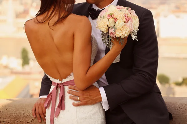 Detalhe de uma noiva e noivo abraçando. Noiva segurando lindo buquê de casamento — Fotografia de Stock