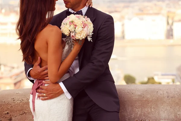 Detalhe de uma noiva e noivo abraçando. Noiva segurando lindo buquê de casamento — Fotografia de Stock