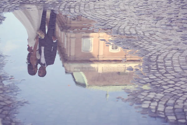 Bride and groom reflected in slop on paved road — Stock Photo, Image