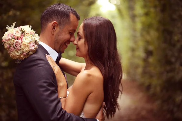 Bruden och brudgummen embracing i trädgården — Stockfoto