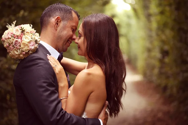 Bruden och brudgummen embracing i trädgården — Stockfoto