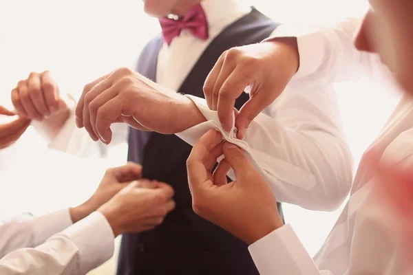 Mains aidant le marié avec des boutons — Photo