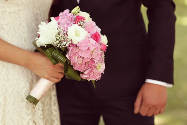 Detail of bride and groom hands with wedding bouquet — Stock Photo, Image