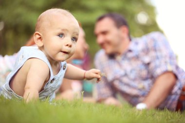 Çim zemin üzerine ailesiyle oturan çocuk