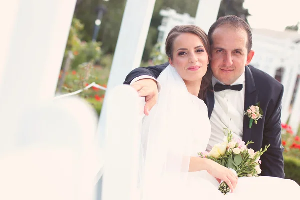 Hochzeitspaar auf einer weißen Bank — Stockfoto