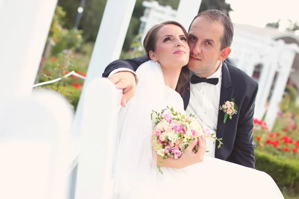 Casamento casal em um banco branco — Fotografia de Stock