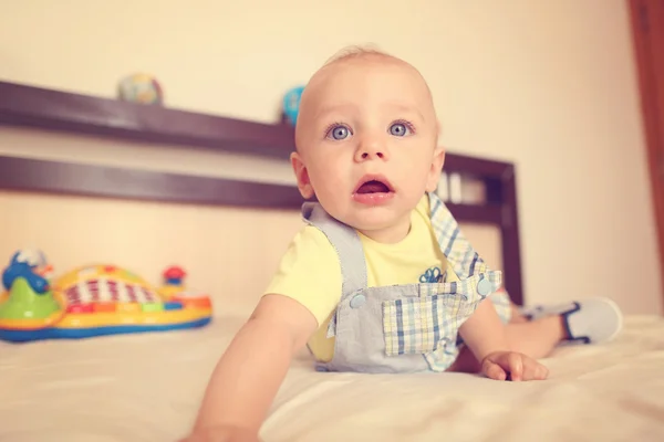 Speelse jong geitje in zijn bed — Stockfoto