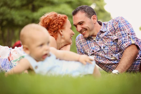 Родители с ребенком сидят на траве — стоковое фото