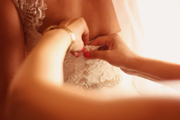 Manos de dama de honor ayudando a la novia con el vestido de novia —  Fotos de Stock