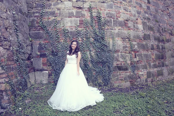 Braut posiert auf einer gemauerten Mauer — Stockfoto