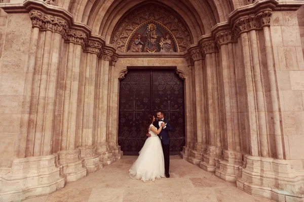 Bruid en bruidegom omarmen voor de kerk — Stockfoto