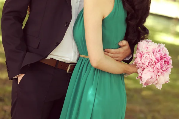 Men hugging his woman. Woman holding bouquet of peonies — Stock Photo, Image