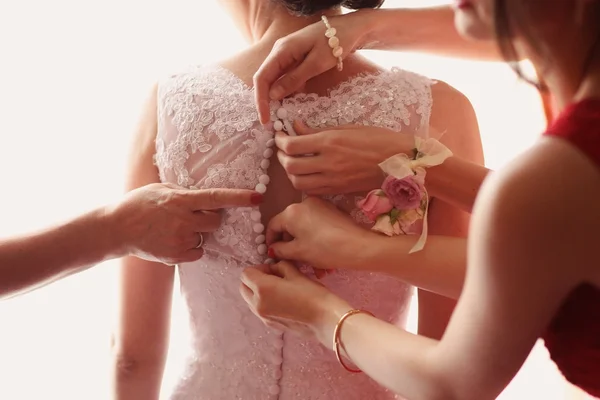 Tärnorna händer hjälper bruden med hennes bröllopsklänning — Stockfoto