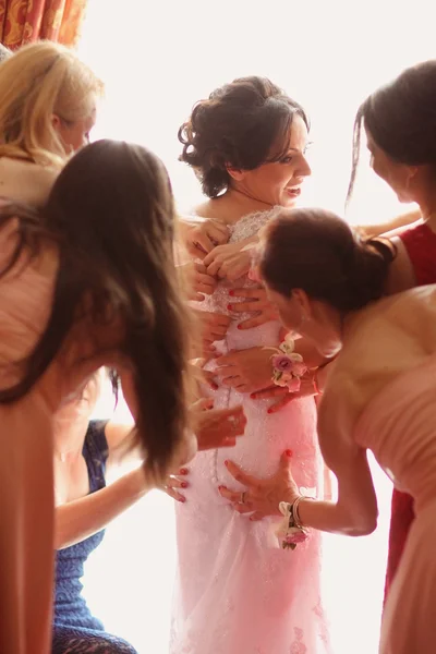 Bruidsmeisjes handen helpen van de bruid met haar trouwjurk — Stockfoto
