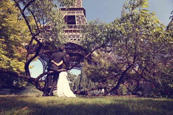 Novia y novio sentados en un árbol cerca de la Torre Eiffel —  Fotos de Stock