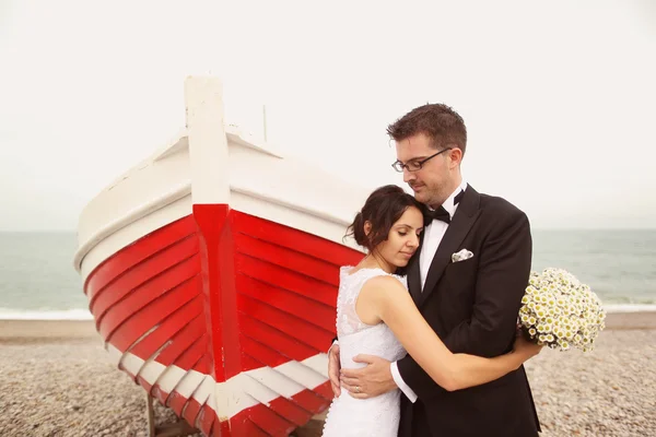 Bride and groom near big, red boat at the ocean — Stock Photo, Image