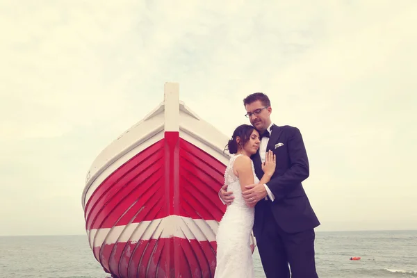 Bride and groom near big, red boat at the ocean — Stock Photo, Image