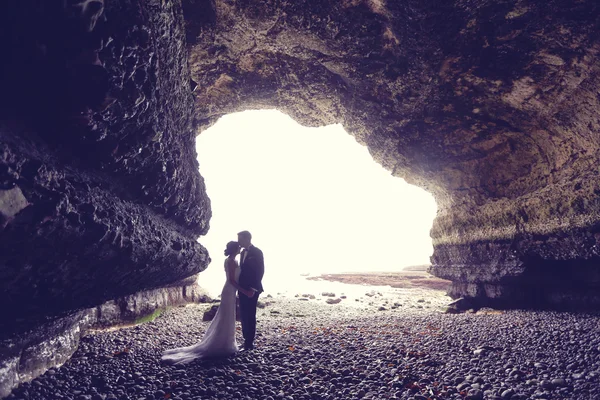 Novia y novio en una cueva cerca del océano —  Fotos de Stock