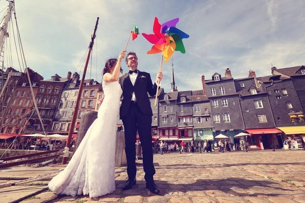Bride and groom playing with windmill propeller — Stock Photo, Image