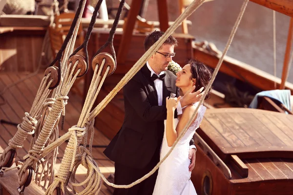 Bruid en bruidegom omarmen in de buurt van grote schip met tekenreeksen — Stockfoto