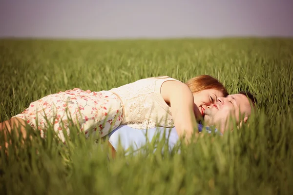 Belo casal alegre deitado na grama verde — Fotografia de Stock