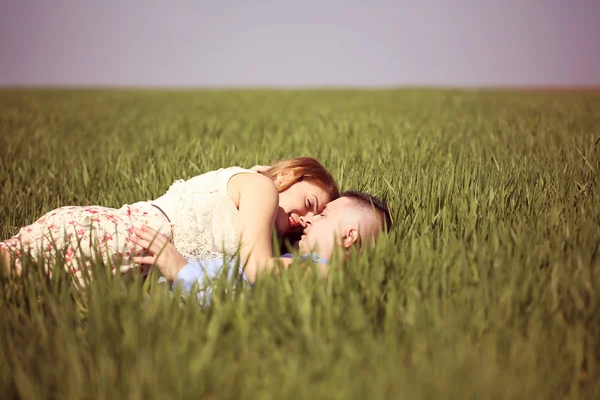 Mooie vrolijke paar liggend op groen gras — Stockfoto