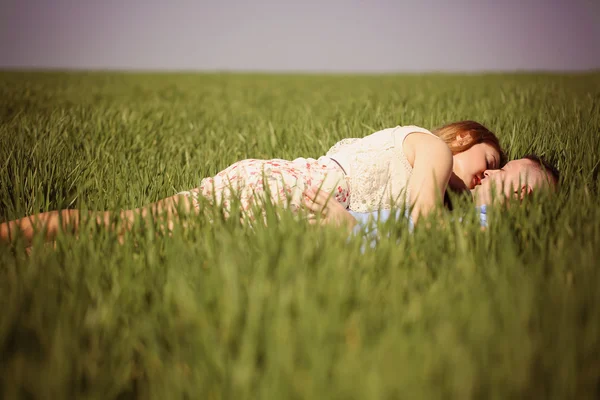 Mooie vrolijke paar liggend op groen gras — Stockfoto