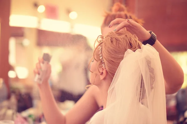 Make up artist applying spray on woman hair — Stock Photo, Image