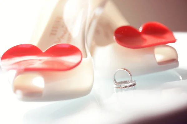 Krásné snubní prsteny poblíž svatební boty s tvarem srdce — Stock fotografie