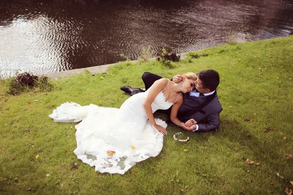 Bruden och brudgummen liggande på gräs — Stockfoto