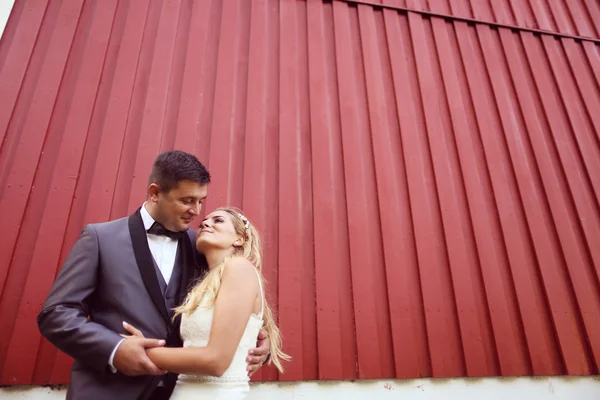 Glada bruden och brudgummen mot röda vägg — Stockfoto