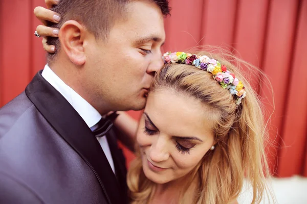 Glada bruden och brudgummen mot röda vägg — Stockfoto